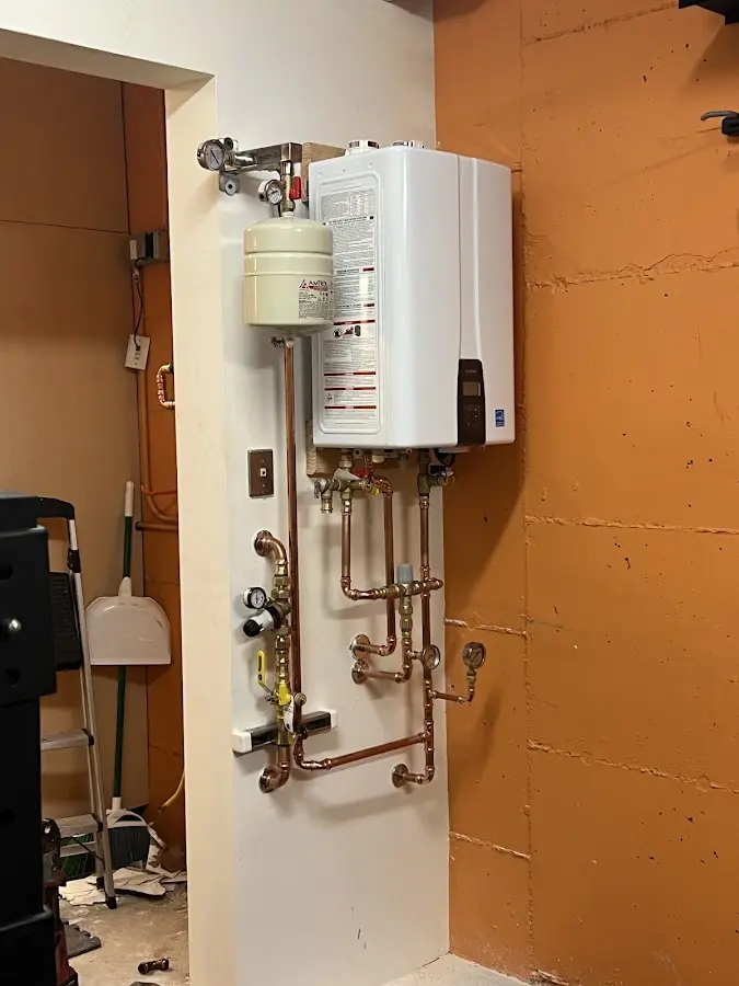 Plumbing technician inspecting water heater connections in Owego